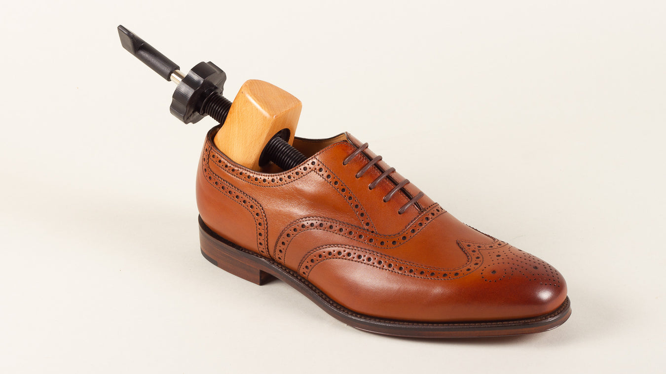 Wooden shoe stretcher in leather shoes by Loake